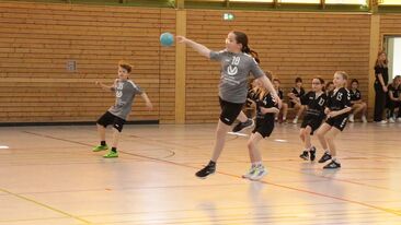 Jugendhandball Spielerin beim Wurf im Angriff in der Sporthalle, dynamische Spielsituation im Nachwuchs-Handballverein