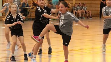 Jugendhandball Spielerinnen im Zweikampf mit Ball während einer Spielsituation in der Sporthalle, dynamischer Nachwuchshandball im Verein
