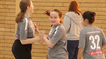 Mehrere Jugendhandball Spielerinnen während einer Mannschaftsszene in der Sporthalle, gemeinsames Spiel im Nachwuchs-Handballverein