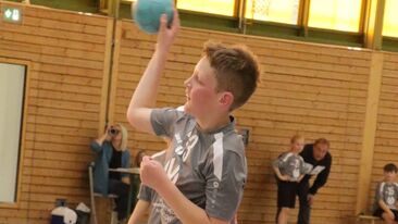 Jugendhandballspieler beim Wurf auf das Tor in der Sporthalle, dynamische Spielsituation im Nachwuchs-Handballverein