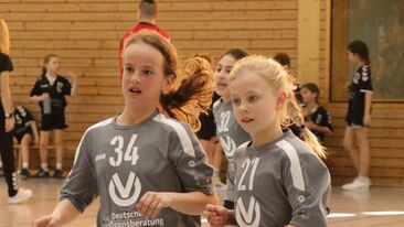 Zwei junge Handballspielerinnen in grauen Trikots beim Jugendhandballspiel in einer Sporthalle, Nachwuchssport im Verein