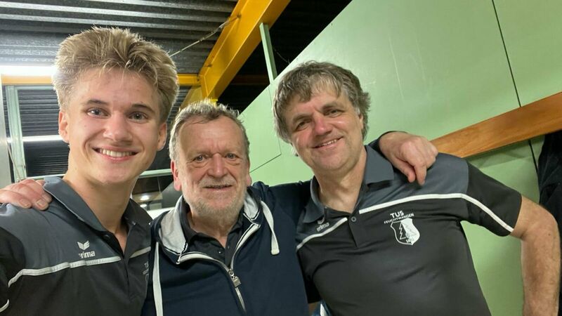 Drei Vereinsmitglieder stehen eng zusammen und lächeln in einer Sporthalle, Teamfoto nach einem gemeinsamen Spiel oder Wettkampf