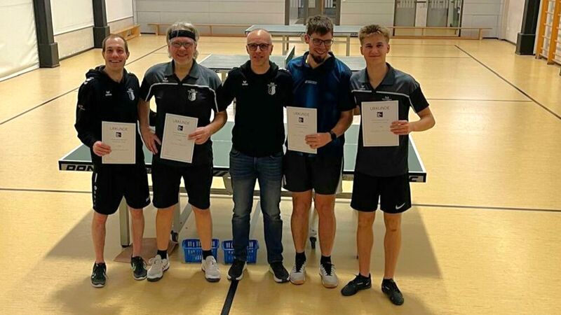 Tischtennis Mannschaft steht mit Urkunden vor einer Tischtennisplatte in der Sporthalle, Siegerehrung oder Auszeichnung im Vereinswettkampf