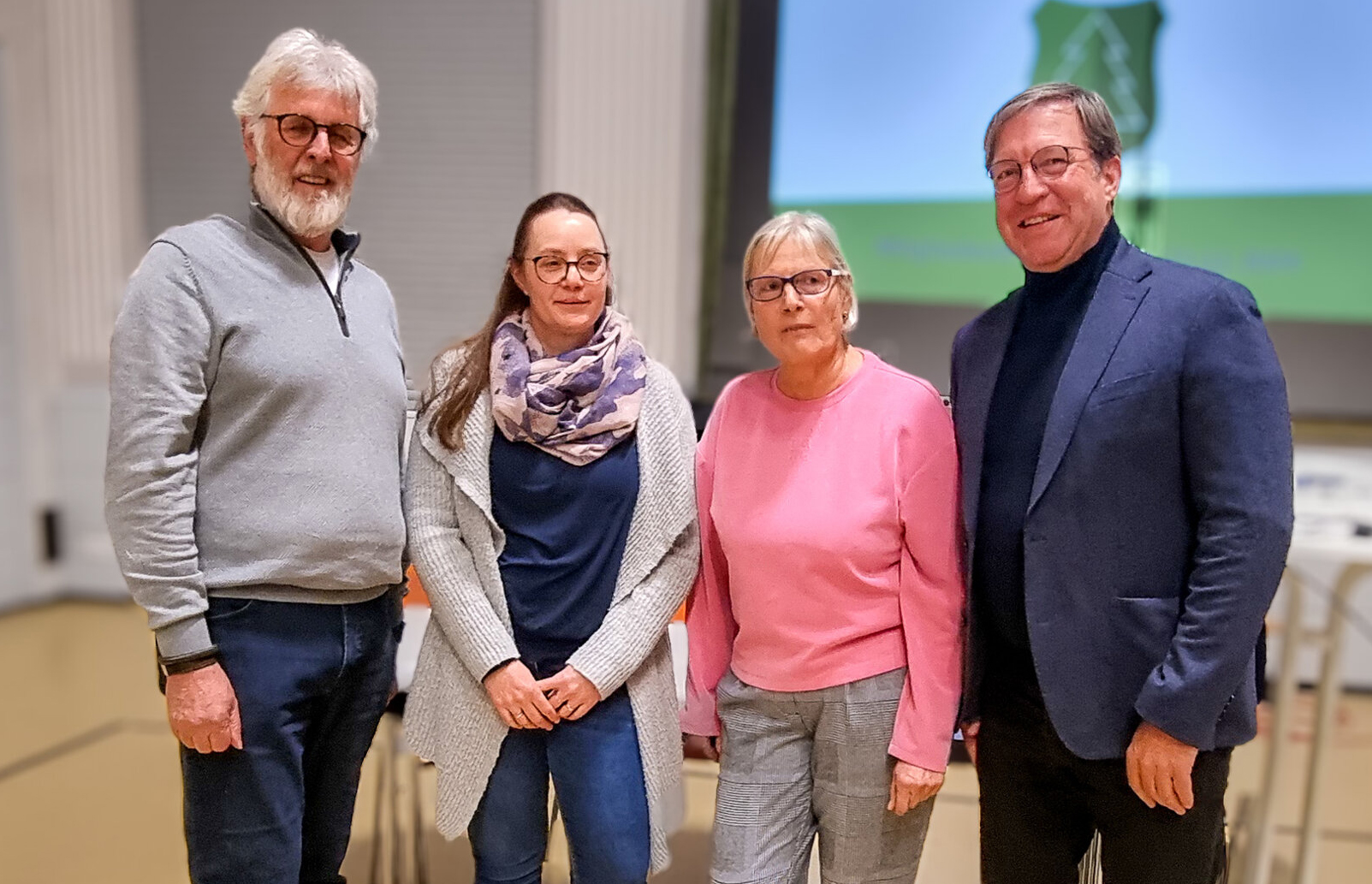 Vier Personen aus dem Vereins- oder Organisationsumfeld stehen gemeinsam bei einer Veranstaltung in einem Saal, Gruppenfoto bei einem Treffen oder einer Versammlung